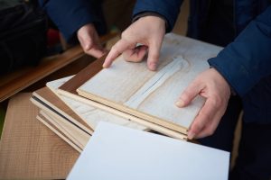 Mãos escolhendo amostras de madeira para revestimento